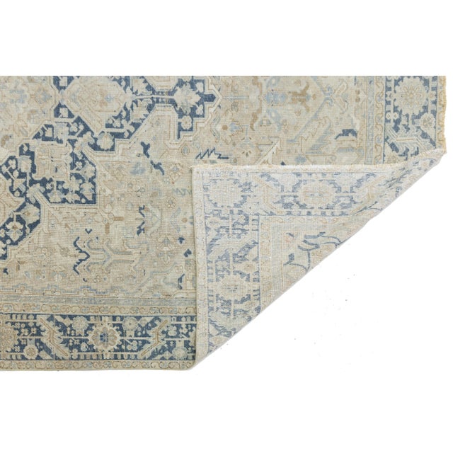 This antique hand-knotted Persian Serapi rug is a stunning example of artisanal craftsmanship. Its warm beige background...