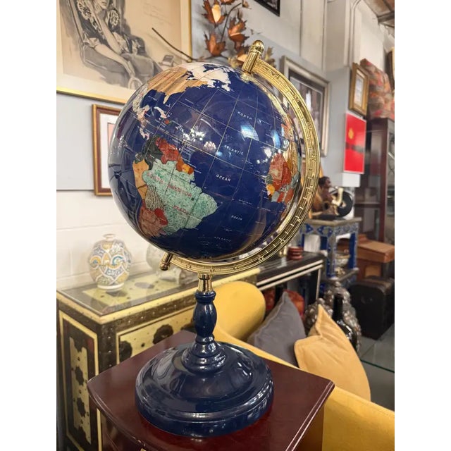 This striking decorative world globe features a richly saturated lapis-blue surface inlaid with detailed continental...