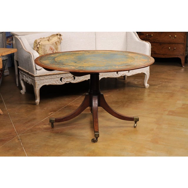 An English Turn of the Century mahogany and leather tilt top centre table with quadripod base and casters. Step into the...