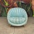 Mid-century clam shell chair with tufted blue fabric and wooden legs.