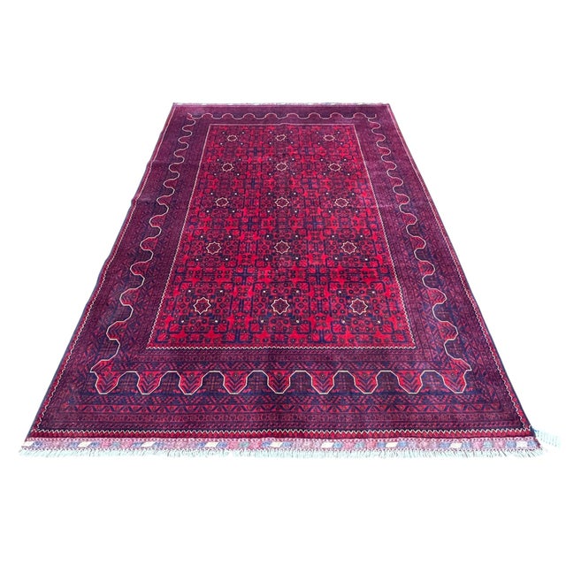 Afghan Turkmen rug, hand knotted in Afghanistan from 100% wool. Measuring 6’7” x 9’8”, this rug features a vibrant red...