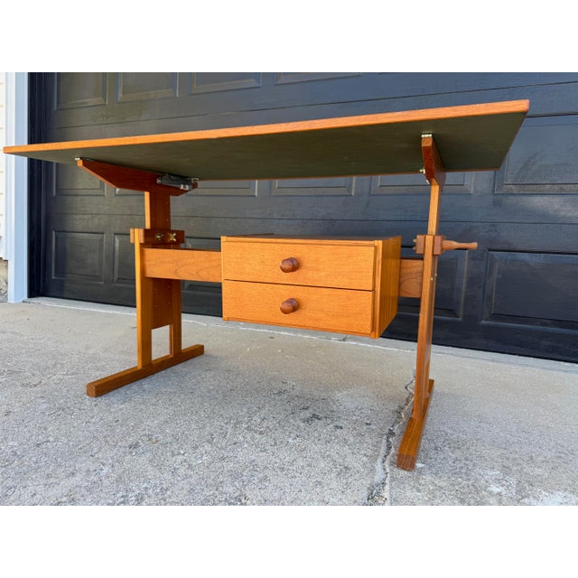 Danish modern, height and tilt adjustable, teak drafting table features a vinyl top and 2 drawer detachable cabinet. The...