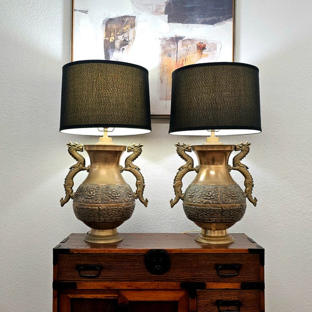 A striking matched pair of repoussé brass table lamps in the Hollywood Regency taste, inspired by the celebrated designs...