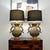 A striking matched pair of repoussé brass table lamps in the Hollywood Regency taste, inspired by the celebrated designs...