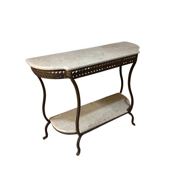 Elegant Hollywood Regency style console table featuring a light beige marble top with a softly shaped serpentine front and...