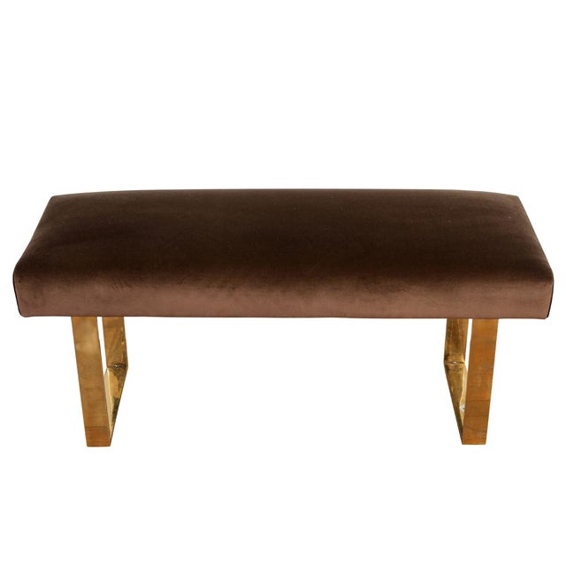 A Mid-Century Modern brass bench newly upholstered in chocolate brown velvet. The polished brass rectangular sled legs are...