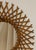 Round rattan wall mirror with radiating crossed-stick sunburst frame. Italian Mid-Century Modern, circa 1960s. Original...