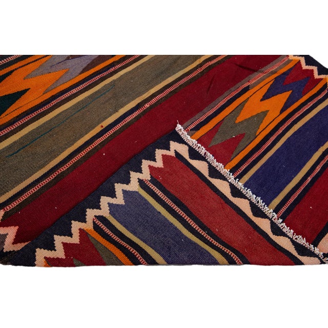 Beautiful kilim handmade wool runner with a red field. This Vintage flatweave rug has orange, purple, and brown accents...