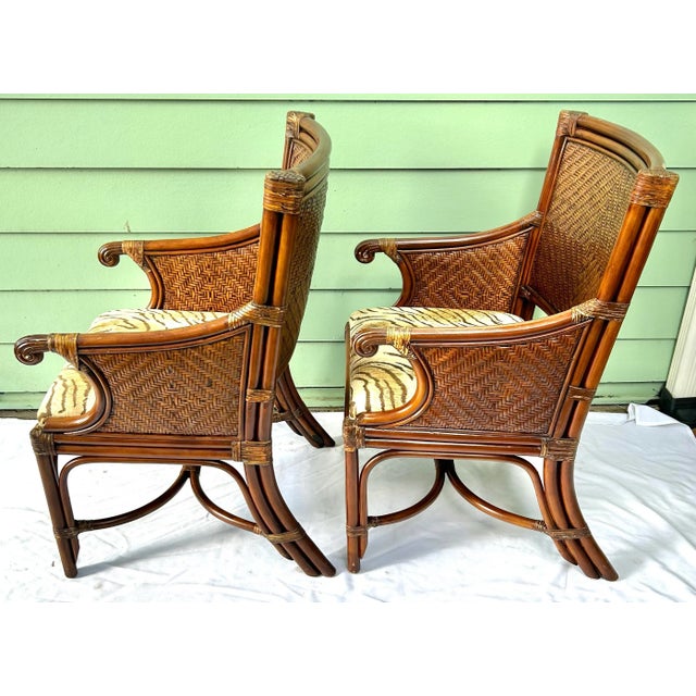 A stylish pair of vintage bamboo and rattan armchairs featuring woven wicker backs and sculptural bent bamboo frames....