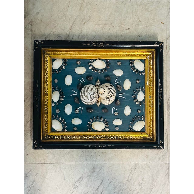 This decorative shellwork plaque features a beautifully balanced arrangement of natural seashells displayed against a rich...