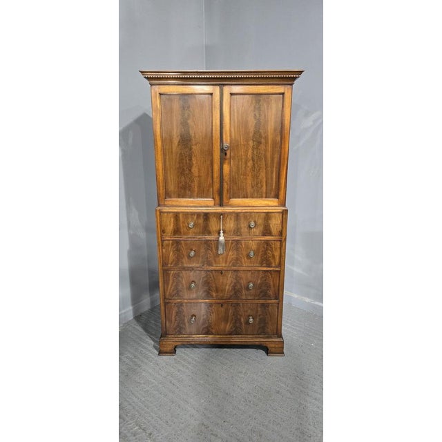 A top quality mahogany linen press by 'Maples' standing on ogee bracket feet with four flame mhahogany drawers, brass...