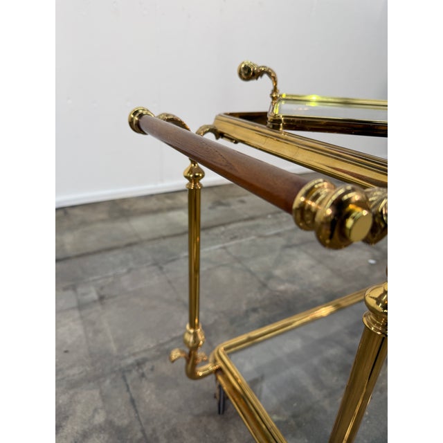 This elegant two-tier bar cart is crafted in polished gilt brass, showcasing refined mid-century workmanship with...