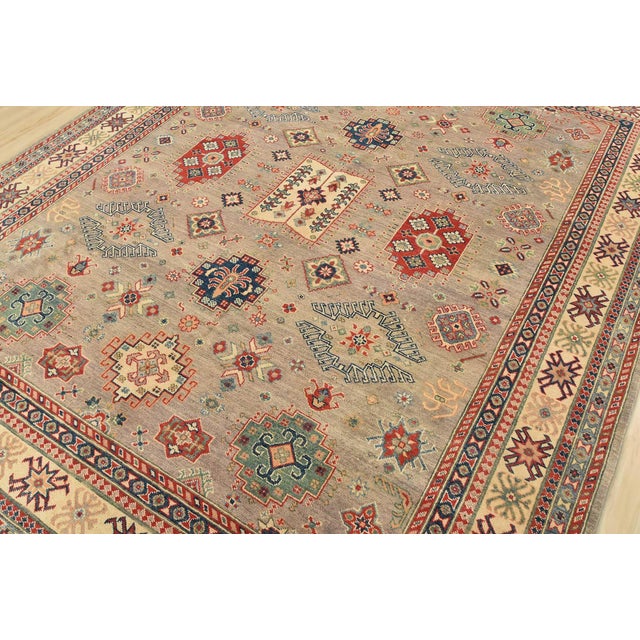 A tribal Caucasian Kazak rug hand-knotted with fine wool on a cotton foundation. This area rug features geometric motifs...