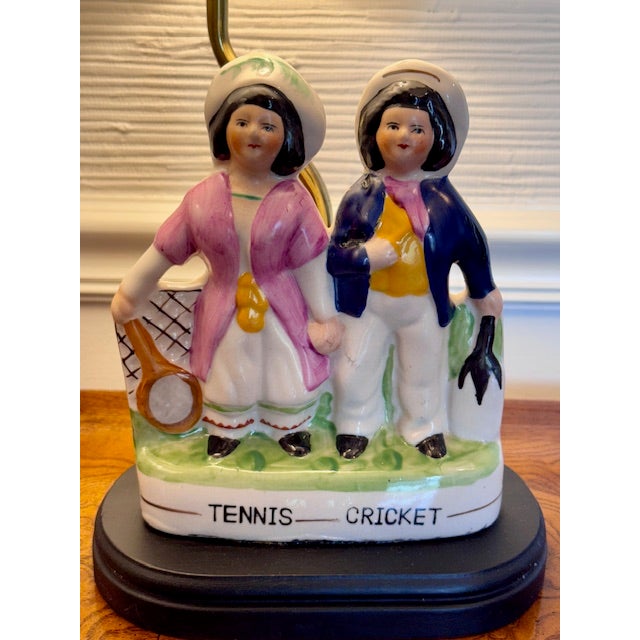 Charming and whimsical, this antique late 19th century&nbsp; lamp features two hand-painted figures labeled "Tennis-...