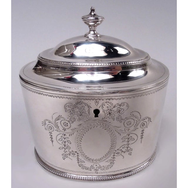 George III sterling silver tea caddy with spoon. Made by Hester Bateman in London in 1784. Oval bowl with straight sides....