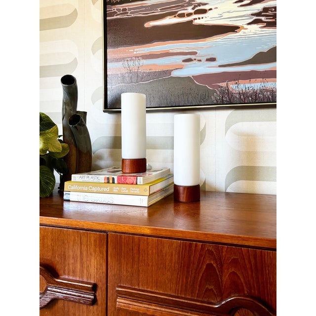 A pair of matching mid century table lamps. Cylinder shapes and minimalist design. Each features a teak base and frosted...