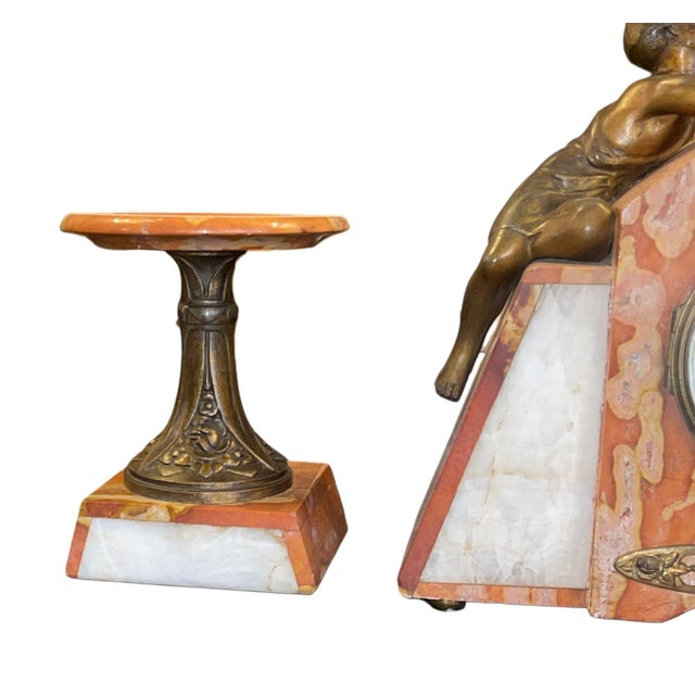 An elegant French marble and spelter clock garniture dating to the late 19th century, featuring a finely cast figural...