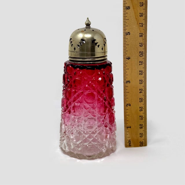 Elevate your antique glassware display with this striking Antique Victorian Cranberry Glass Sugar Shaker. Standing 5.5...