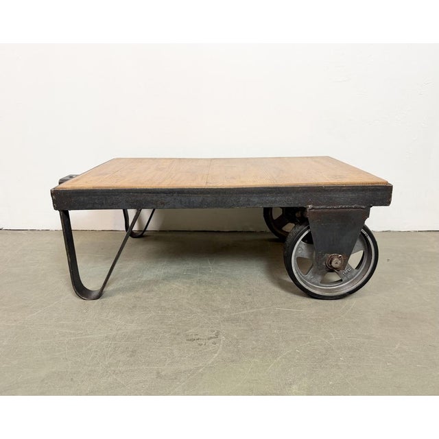 Former pallet truck from a factory now serves as a coffee table. It features a black iron construction with two original...