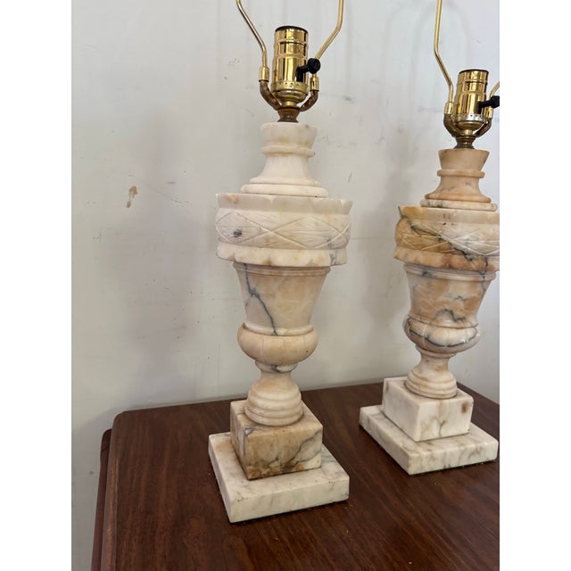 A pair of vintage marble lamp bases. Beautifully carved on pedestals. The lamps come with harps and finials. No shades...