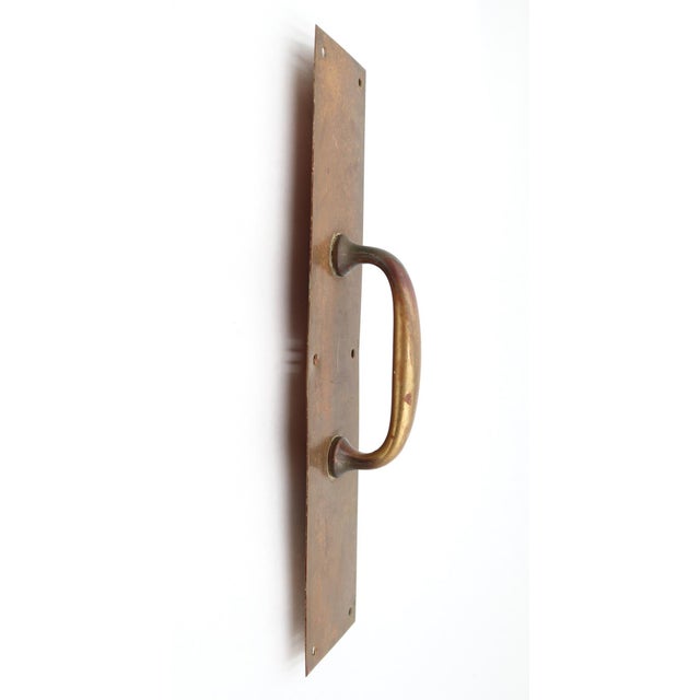 Commercial style door pull made of brass with a patina finish. The original mounting screws are not available. Good...