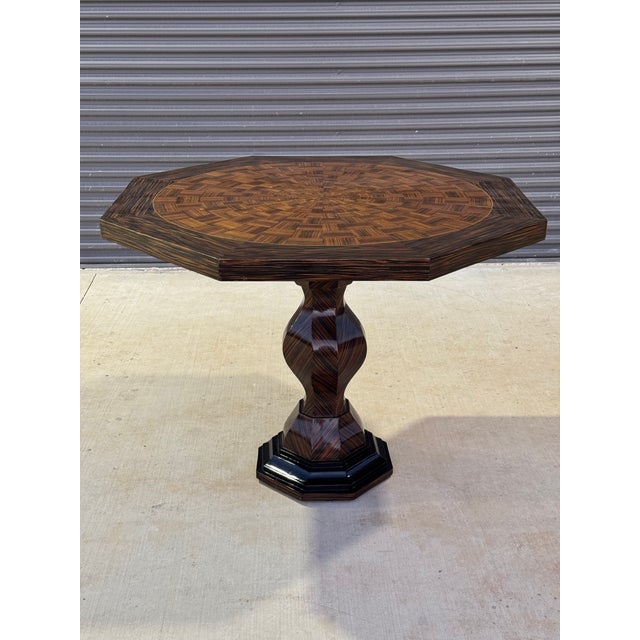 A French Art Deco-style octagonal pedestal center or foyer table crafted from zebrano wood with ebonized detailing and a...
