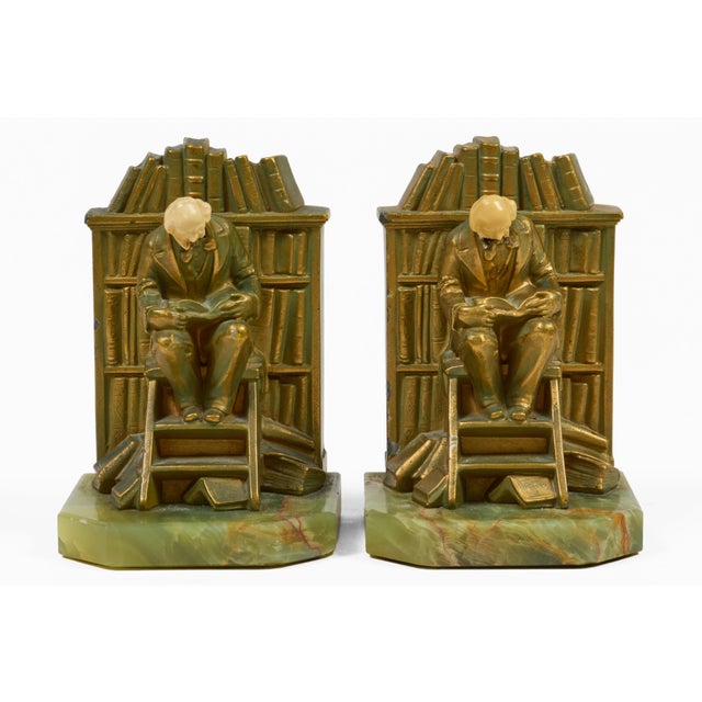 These Art Deco bookends, made by J. B. Hirsch Foundry, depict a scholar sitting on a step ladder reading a book against...