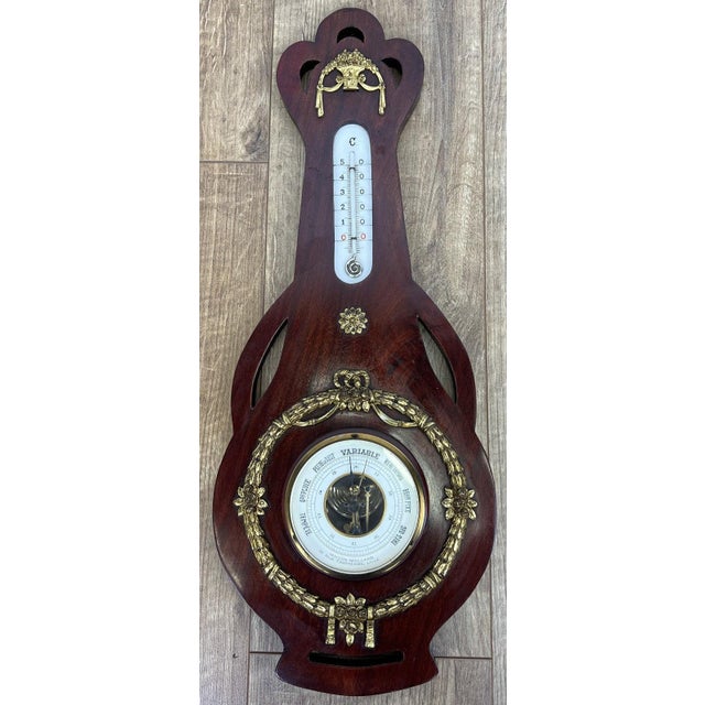 A beautifully decorative vintage brass and mahogany barometer featuring elegant classical styling and richly detailed...