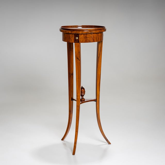 Elegant Biedermeier gueridon standing on three gently curved, tapering legs, connected by a trefoil stretcher adorned with...