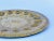 Vintage brass tray with intricately tooled surface and round form. Integrated brass hook affixed on the back for hanging.