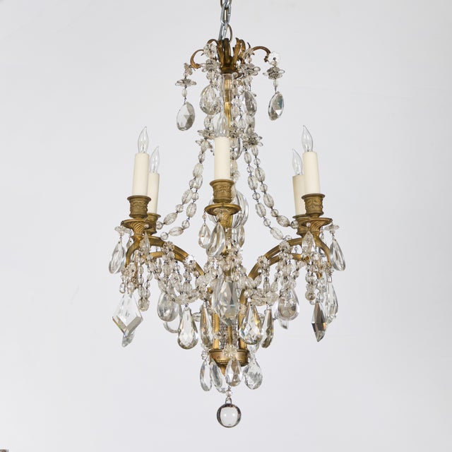 A charming, petite gilt-bronze, 6 lights, chandelier with crystal pendeloques and crystal chains, supported by a crystal...