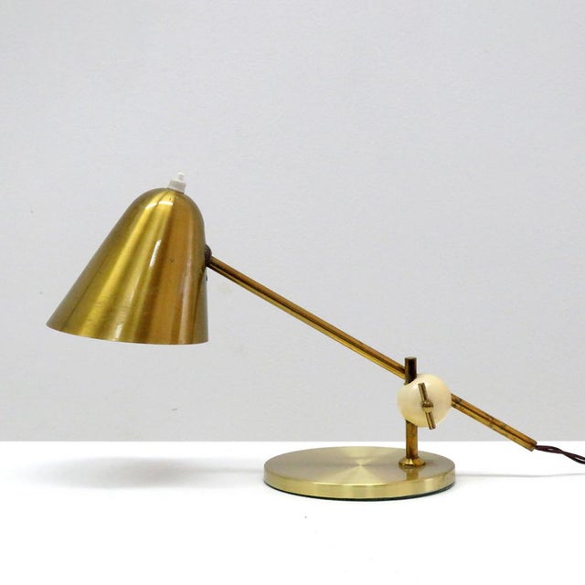 Wonderful brass table lamp by Jacques Biny with wonderful patina, adjustable at the hood and the white bakelite ball...