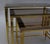 Set of three nesting tables in gilt metal, with fluted legs supporting a smoked glass top. Work from the 20th century.
