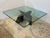 Design Plus Gallery presents a Sculptural Glass Top Coffee Table. This table has a square glass top with a smoky tint and...