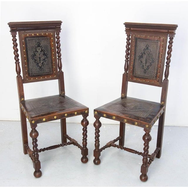 Pair of oak and leather chairs, Middle East Embossed leather The leather has marks of use but it it uin good condition....