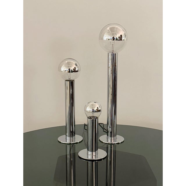 A set of 3 space age chrome pillar lamps with staggered heights. Shown with varying size chrome dipped lightbulbs. Sourced...