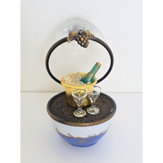A rare Limoges France La Gloriette painted porcelain glass domed egg which opens to reveal a very detailed champagne...