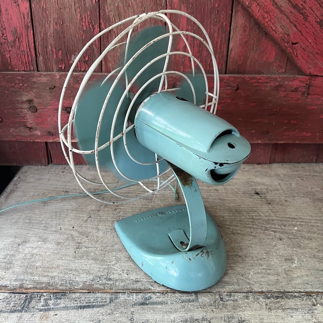 This vintage General Electric desk fan from the 1950s features a charming aqua blue finish with oscillating functionality....