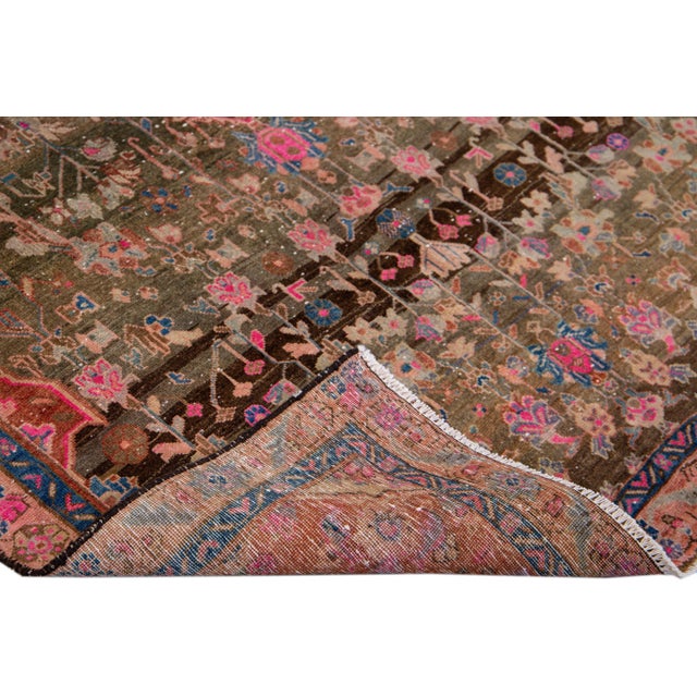 Beautiful vintage distressed medallion hand-knotted wool rug with a brown field. This rug has pink and blue accents in a...