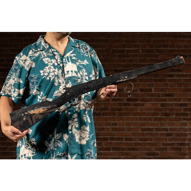 Hand-carved wooden figural gun trade sign with original iron hanging mounts. Measuring over three feet in length, this...