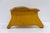 A low, sculptural footstool with a hand-shaped, live-edge wood top in a warm honey tone, showing natural grain variation...