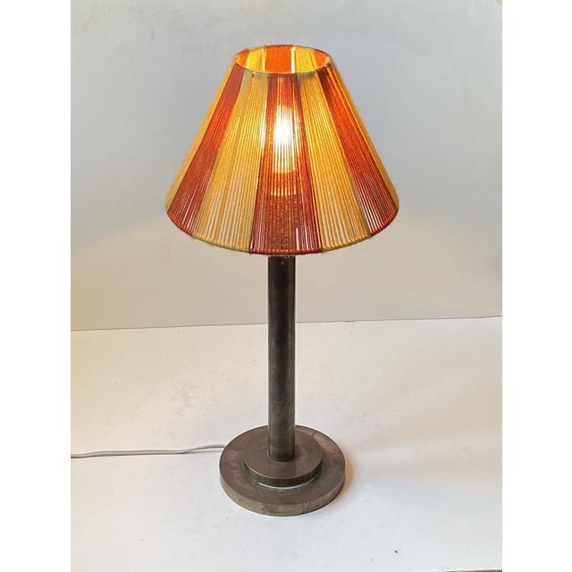 Simple table lamp executed in patinated brass and featuring a stepped architecturally perceived base and wool string shade...