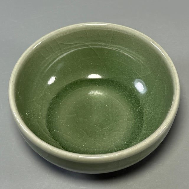 This antique Chinese Longquan celadon cup has a smooth rounded body, covered in rich olive-green glaze with natural...