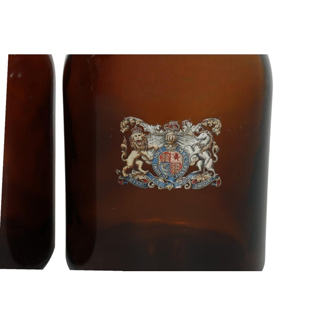 A pair of World War 1 era British brown glass armorial demijohns. Decorated in front with the Royal Coat of Arms of the...