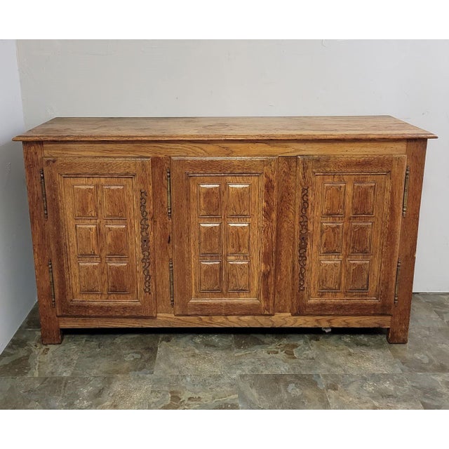 A striking oak credenza in the Spanish Revival style, dating from the mid-20th century. The paneled front is richly...