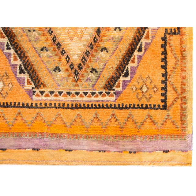 A brilliant vintage mid-20th century Moroccan rug with a central stylized floral diamond surrounded by repeated petite...