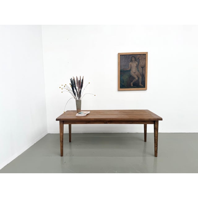 Farmhouse table, featuring a pegged solid oak top and tapered pine legs, made in France in the 1950s. The pegged solid oak...