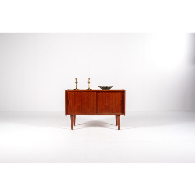 This compact mid-century modern teak cabinet is a refined example of Scandinavian furniture design from the 1960s. with...