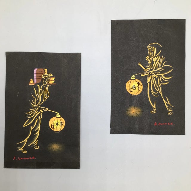 A Pair of framed and signed paintings of 2 Asian people carrying a lantern and supplies. They are signed by the artist....