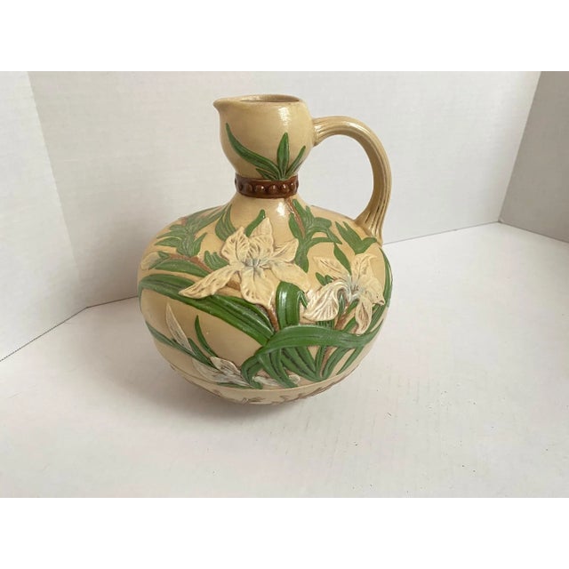 Vintage Majolica style natural colored ceramic jug with embossed floral design relief of white irises, blue floral vine,...